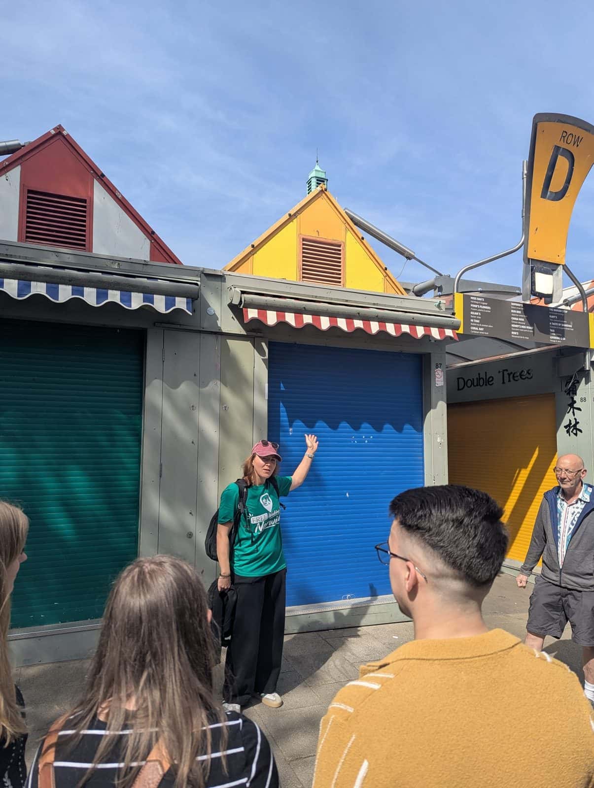 Guide pointing out the stalls at Norwich Market to a tour group