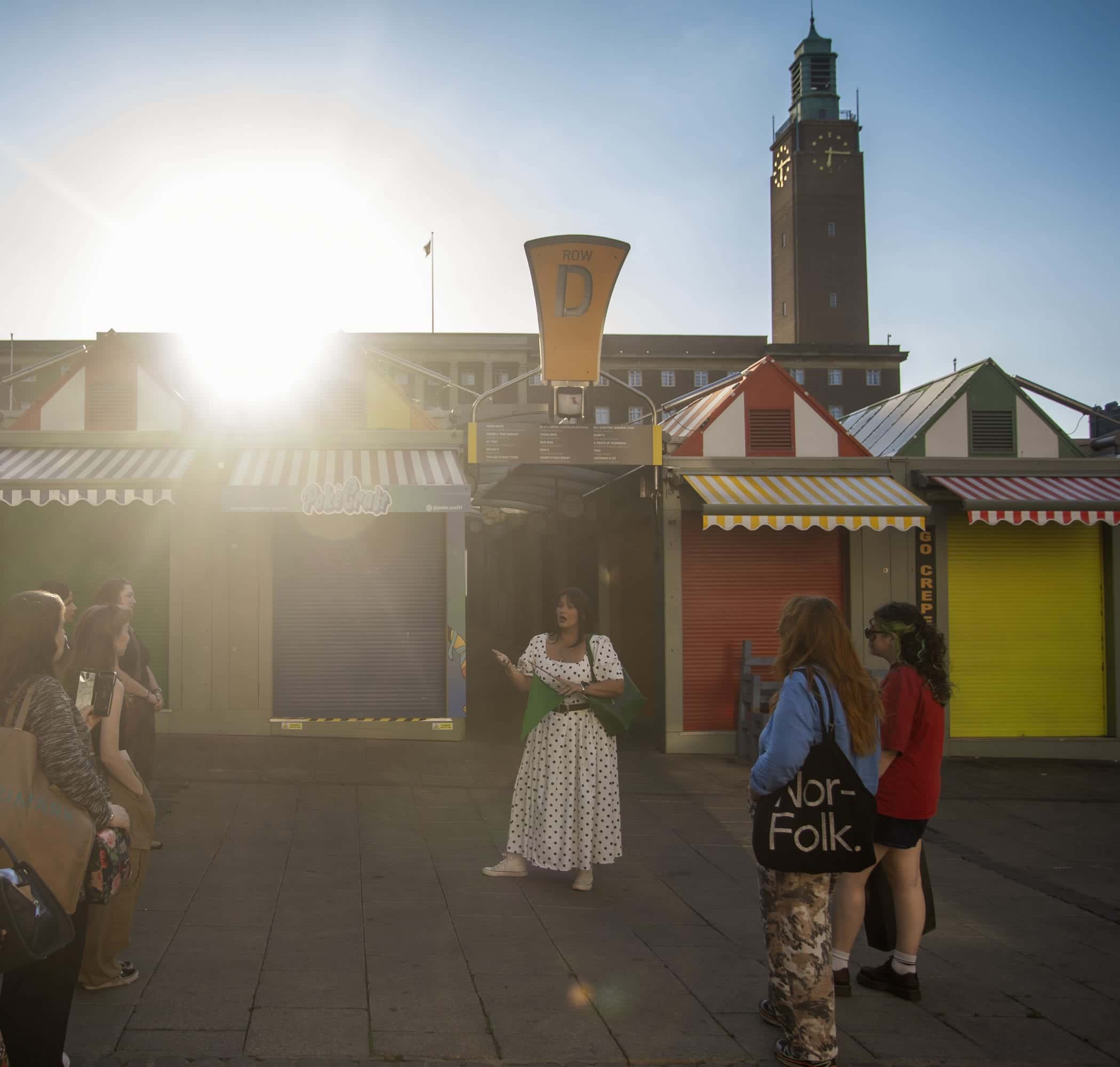 Guide finishing the tour at Norwich Market with City Hall's clock tower behind