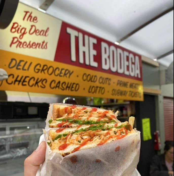 A loaded Big Deal's Bodega sandwich under the deli signage on Norwich Market.